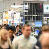 Viele Messebesucher in einer Ausstellungshalle mit verschiedenen Ständen und Bannern im Hintergrund.